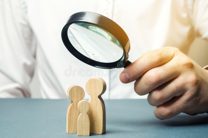 Ένα πρόσωπο εξετάζει τους οικογενειακούς αριθμούς μέσω μιας ενίσχυσης - γυαλί Η μελέτη της οικογενειακής σύνθεσης, στατιστικές Έλ στοκ φωτογραφία